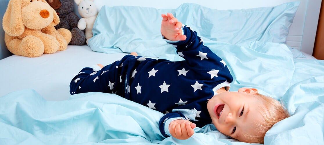Baby in star-patterned pajamas on bed