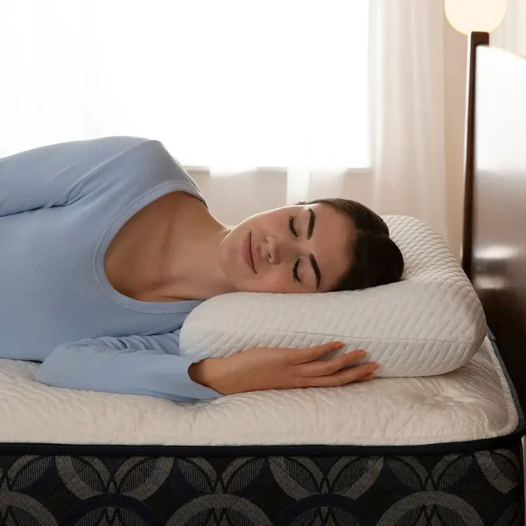 Woman sleeping on a bed with a white Serta Nightstar pillow