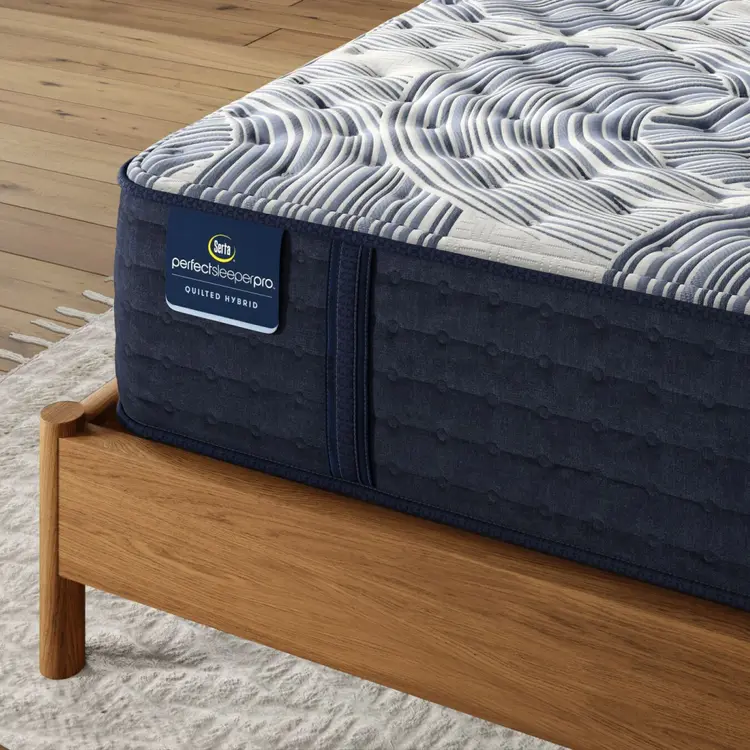 Corner of Perfect Sleeper Pro Geneva Firm mattress sitting in a brown bedframe || Level: Level 2 || Feel: Firm