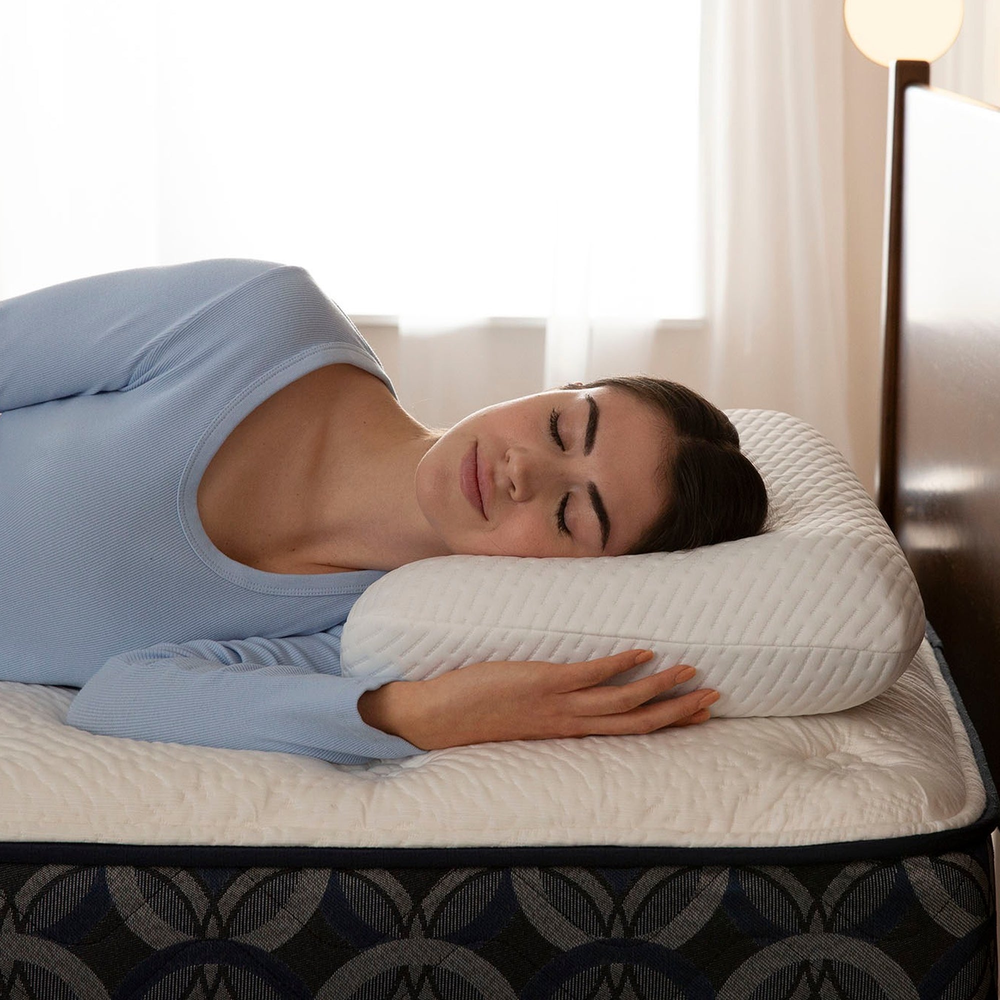 Woman sleeping on a bed with a white Serta Nightstar pillow